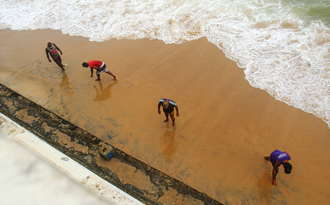Homens catavam moedas, correntes e outros objetos trazidos pelo mar na Barra.